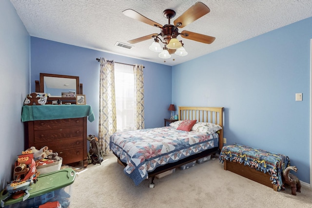 bedroom featuring a textured ceiling, carpet, visible vents, and ceiling fan