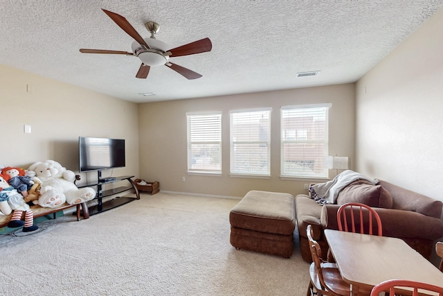 carpeted living area with visible vents, plenty of natural light, a textured ceiling, and ceiling fan