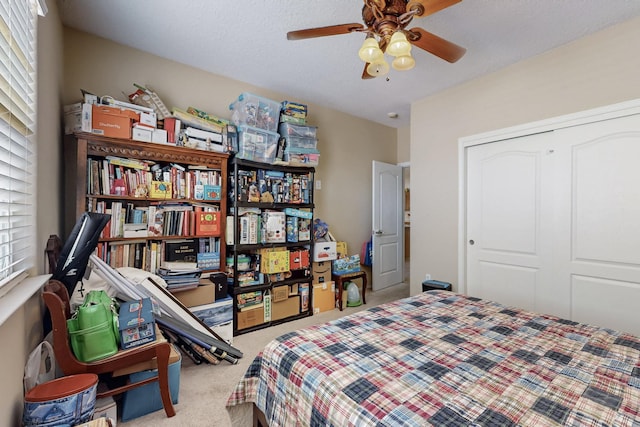 carpeted bedroom featuring ceiling fan, a closet, and a textured ceiling