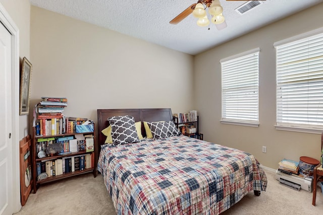 bedroom with a closet, visible vents, a textured ceiling, and carpet