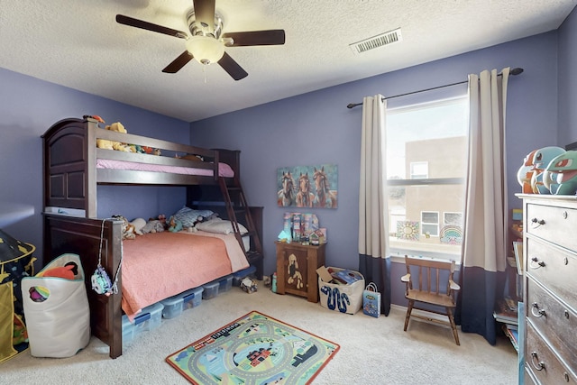 carpeted bedroom featuring visible vents, a textured ceiling, and a ceiling fan