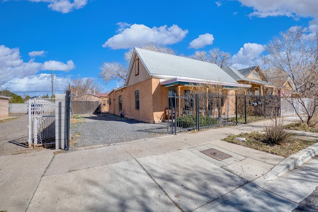 view of home's exterior featuring driveway, a fenced front yard, a gate, and stucco siding