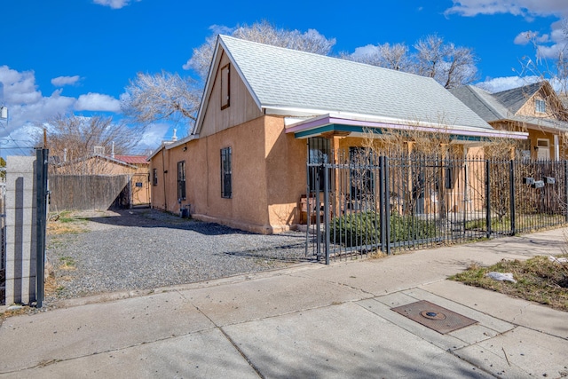 view of home's exterior featuring fence private yard, roof with shingles, a gate, and stucco siding