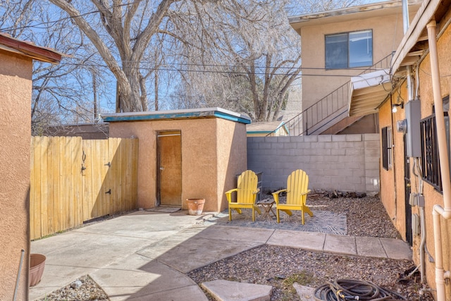 view of patio featuring an outbuilding, a fenced backyard, and a storage unit