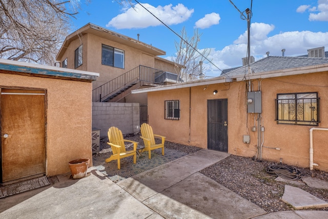 rear view of property featuring fence, a patio, and stucco siding