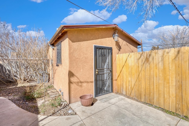 doorway to property featuring fence and stucco siding