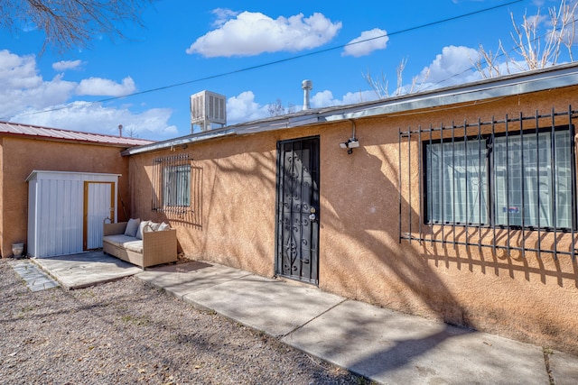 entrance to property featuring metal roof, a patio, and stucco siding