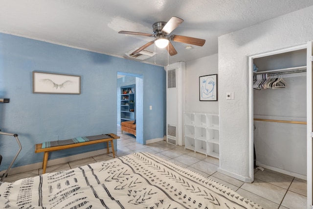 tiled bedroom featuring baseboards, visible vents, ceiling fan, a textured ceiling, and a closet