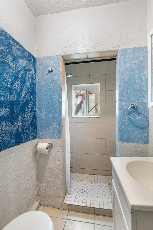 bathroom with a textured wall, tile patterned flooring, toilet, vanity, and a shower stall