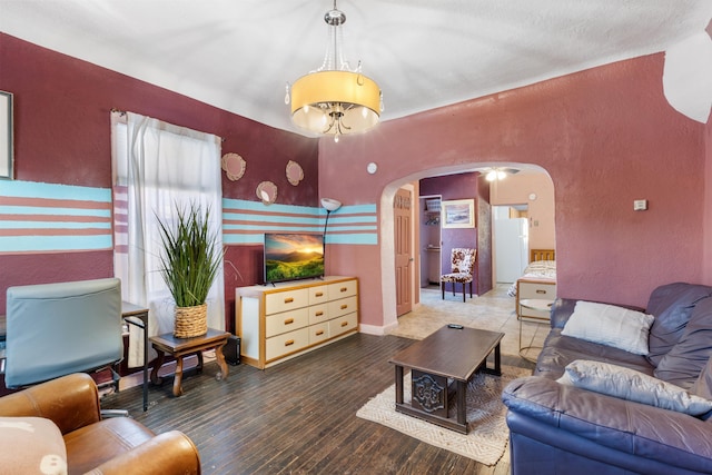 living area with baseboards, arched walkways, wood finished floors, and a textured wall