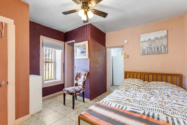 bedroom featuring a ceiling fan, light tile patterned flooring, a textured wall, and a textured ceiling