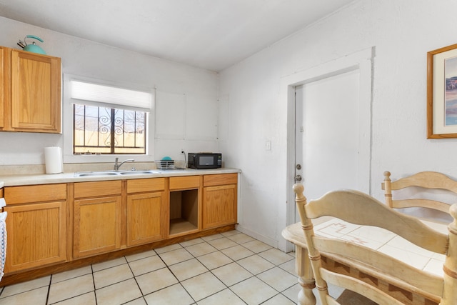 kitchen featuring light tile patterned floors, black microwave, light countertops, and a sink