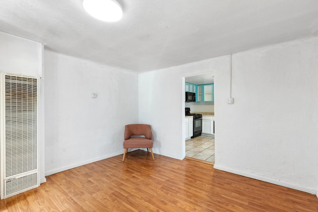 unfurnished room with light wood-style floors and a heating unit