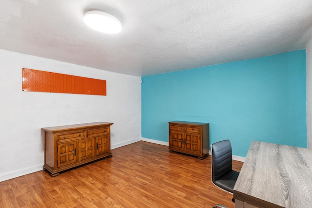 home office with a textured ceiling, baseboards, and wood finished floors