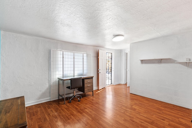 unfurnished office featuring a textured wall, a textured ceiling, and wood finished floors