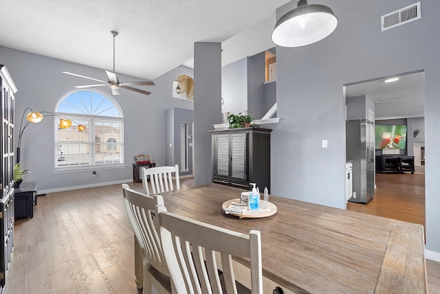 dining room with vaulted ceiling, light wood-type flooring, visible vents, and a ceiling fan