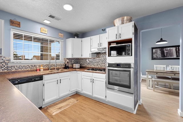 kitchen with visible vents, light wood-style flooring, appliances with stainless steel finishes, a sink, and under cabinet range hood