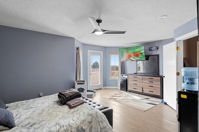 bedroom featuring a ceiling fan, light wood-type flooring, access to exterior, and a textured ceiling