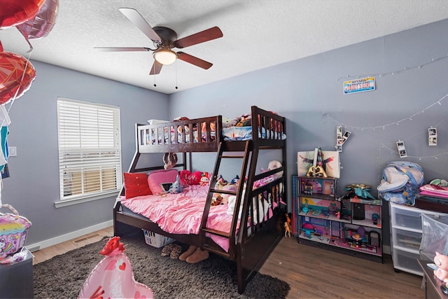 bedroom with visible vents, a ceiling fan, a textured ceiling, wood finished floors, and baseboards