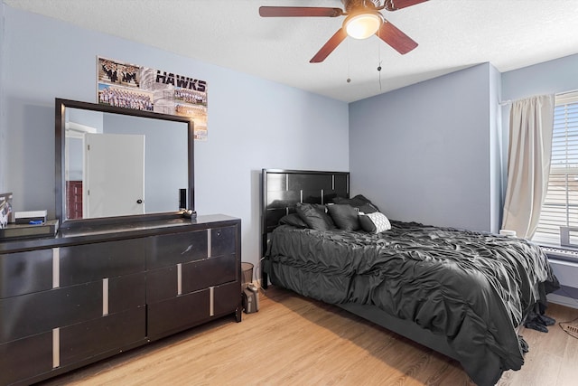 bedroom with ceiling fan, a textured ceiling, and wood finished floors