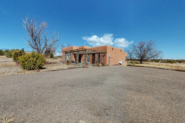 adobe home featuring gravel driveway and stucco siding