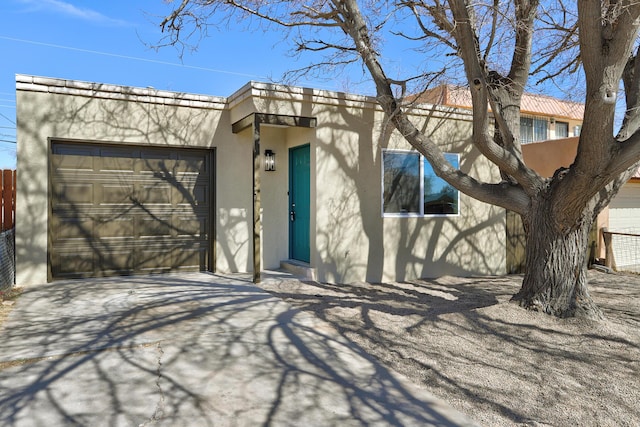 view of front facade with concrete driveway, an attached garage, and stucco siding