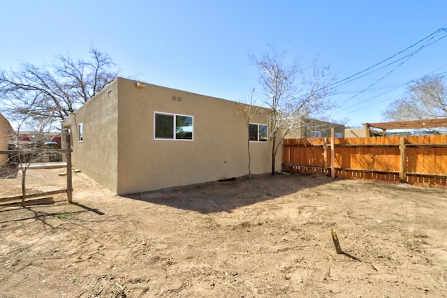 back of house with fence and stucco siding