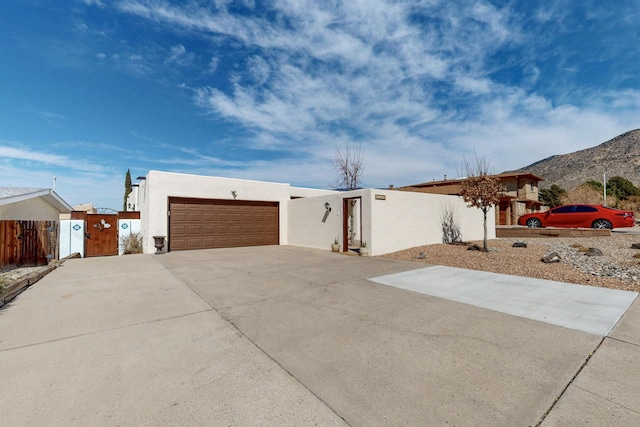 view of front of home with stucco siding, concrete driveway, an attached garage, and fence