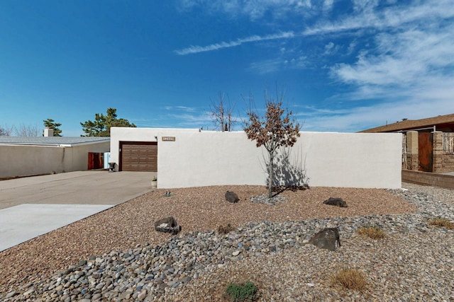 view of home's exterior with stucco siding, driveway, and fence