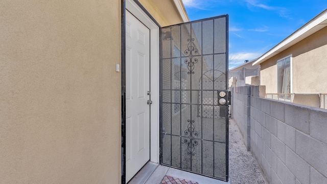 view of exterior entry featuring a gate and stucco siding