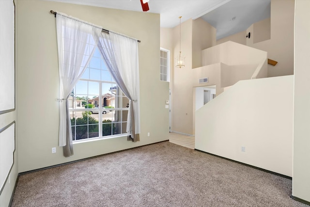 unfurnished room with visible vents, ceiling fan with notable chandelier, high vaulted ceiling, and carpet floors