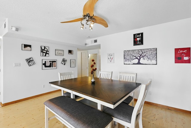 dining area featuring a textured ceiling, visible vents, a ceiling fan, and light wood finished floors