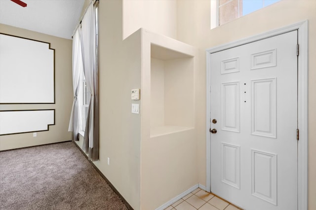 foyer with light colored carpet, baseboards, and ceiling fan