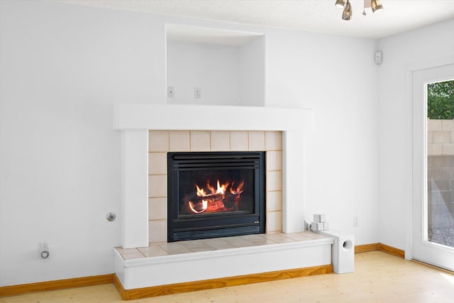 details featuring a tiled fireplace, wood finished floors, and baseboards