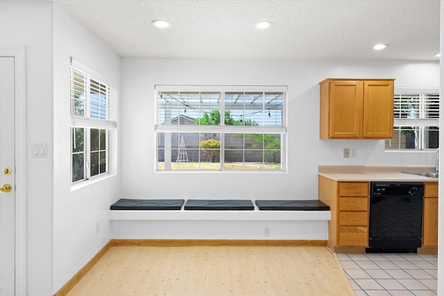 kitchen with light wood finished floors, dishwasher, a textured ceiling, and light countertops