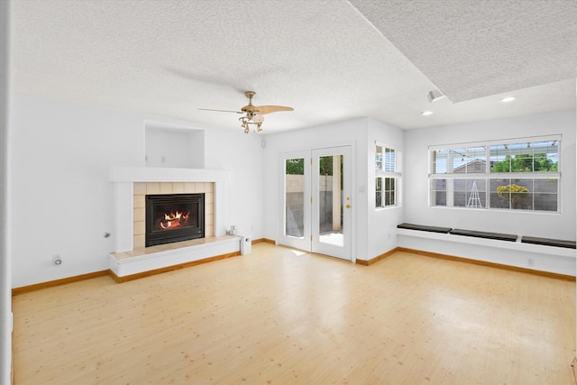 unfurnished living room with wood finished floors, baseboards, recessed lighting, a textured ceiling, and a tiled fireplace