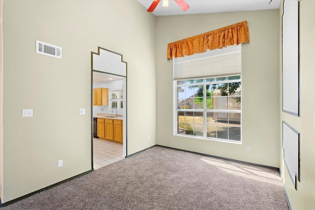 unfurnished bedroom featuring visible vents, connected bathroom, light carpet, high vaulted ceiling, and a sink