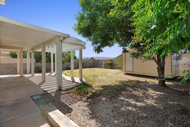 view of yard featuring an outbuilding, a patio area, and a fenced backyard