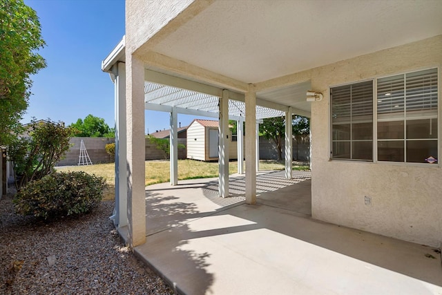 view of patio / terrace with a fenced backyard, a storage unit, an outdoor structure, and a pergola