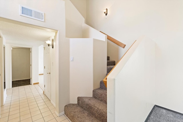 staircase with tile patterned flooring, visible vents, and baseboards