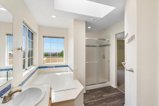 full bathroom with a garden tub, a stall shower, a sink, wood finished floors, and a skylight