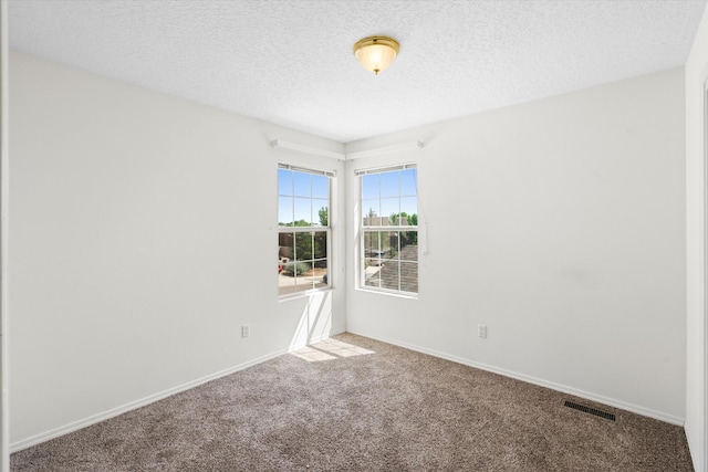 carpeted empty room with baseboards, visible vents, and a textured ceiling