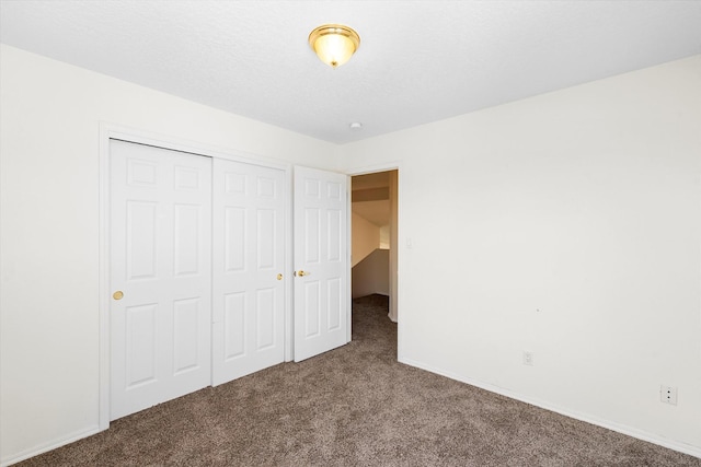 unfurnished bedroom with a closet, a textured ceiling, baseboards, and carpet floors