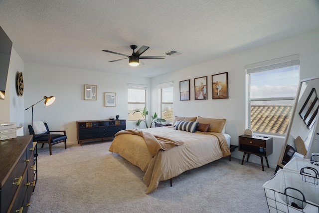 bedroom featuring light colored carpet, visible vents, and a textured ceiling