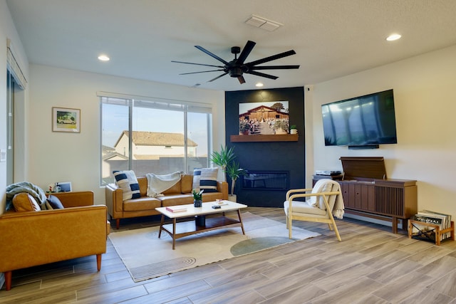 living room featuring a ceiling fan, wood finish floors, visible vents, and recessed lighting