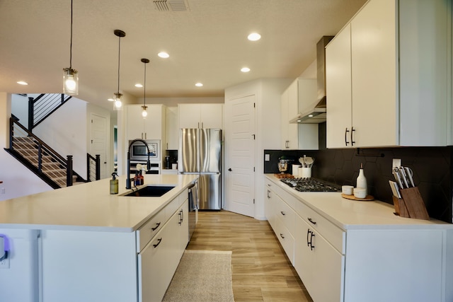 kitchen with stainless steel appliances, visible vents, light wood-style flooring, decorative backsplash, and a sink