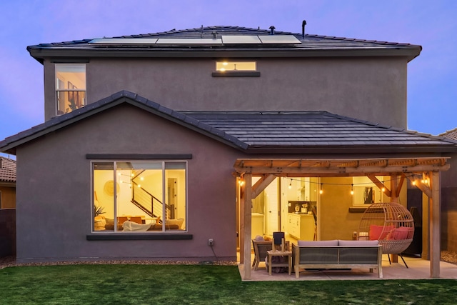 back of house featuring solar panels, a patio area, an outdoor living space, and stucco siding