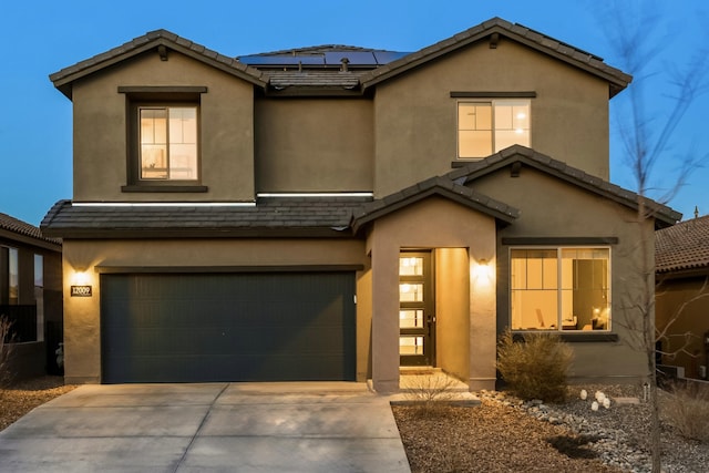 traditional-style home featuring stucco siding, concrete driveway, roof mounted solar panels, a garage, and a tiled roof