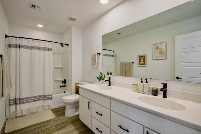 bathroom with toilet, wood finish floors, a sink, and visible vents