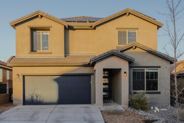 traditional-style house with a garage, concrete driveway, a tile roof, roof mounted solar panels, and stucco siding